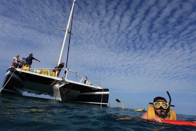 Persona haciendo snorkel junto a una embarcación en Los Cabos